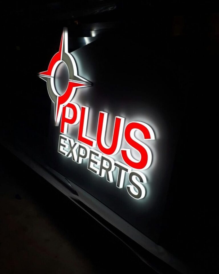 Red and white backlit acrylic logo letters at night