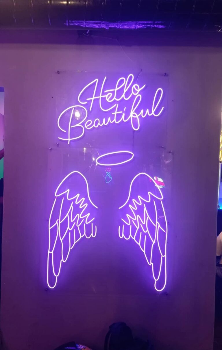Angel wings and Hello Beautiful neon wall installed in a cafe
