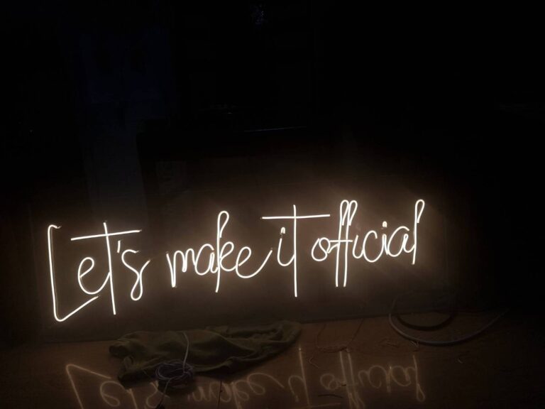 Warm white script neon sign reading Let's make it official